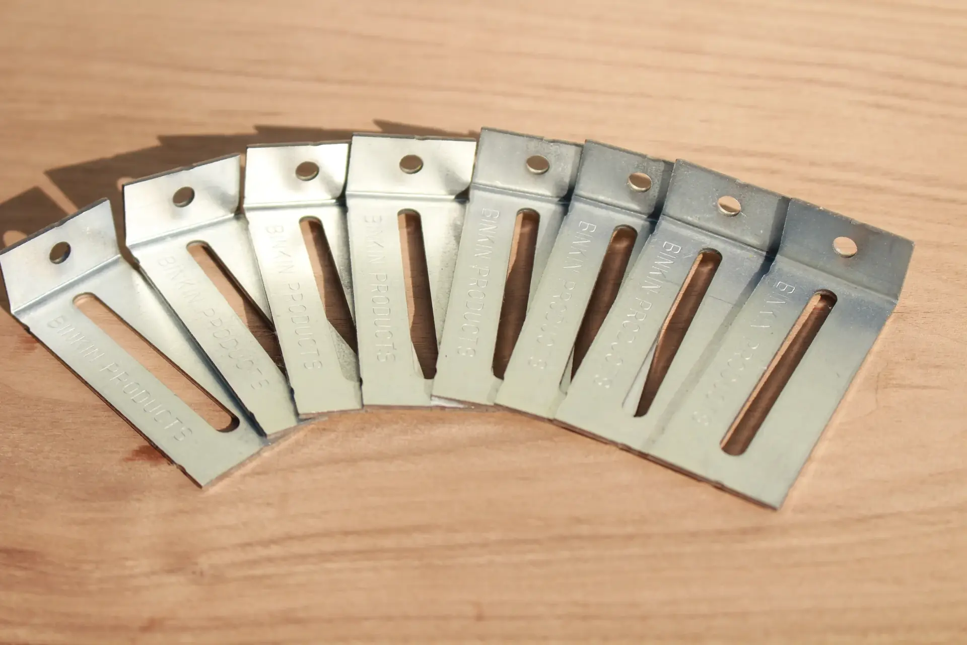 Eight galvanized BINKIN brackets fanned out on a workbench